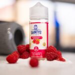 Dainty's 100ml E-Liquid Shortfill on a table with fresh raspberries